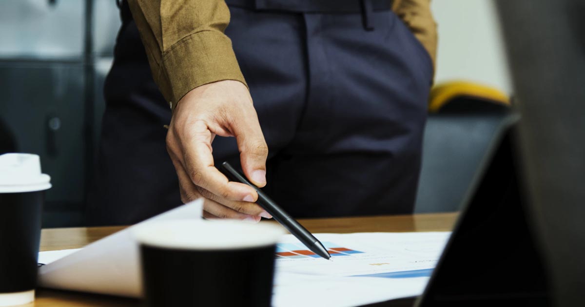 person pointing at paper with a pen
