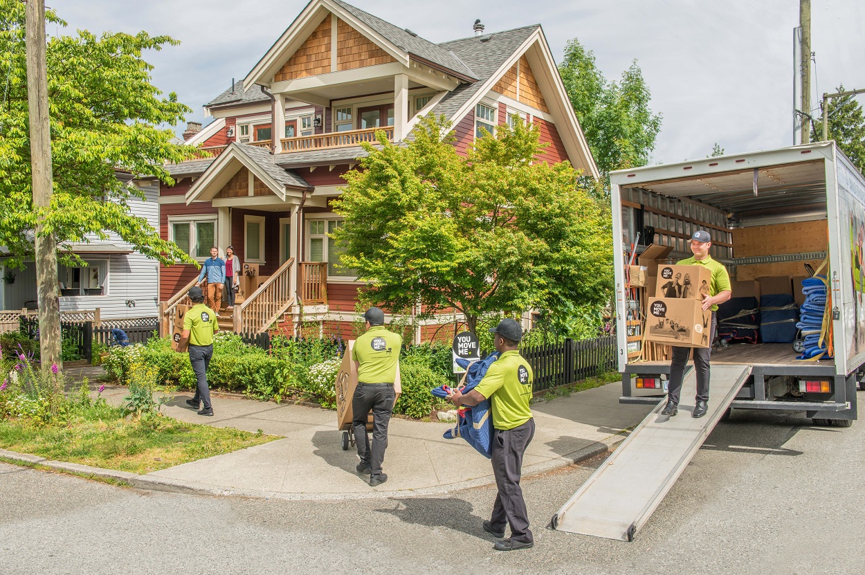 four movers moving boxes from the truck to a new home