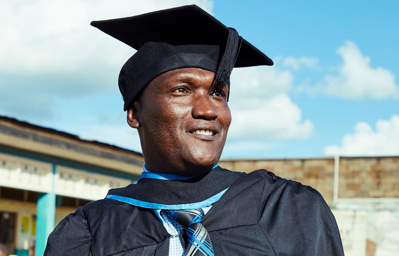 A Justice Defenders graduate beams while wearing a cap and gown.