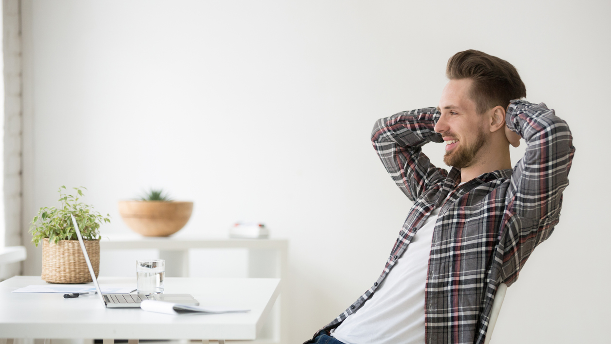 Man sitting in chair relaxed in front of laptop. 