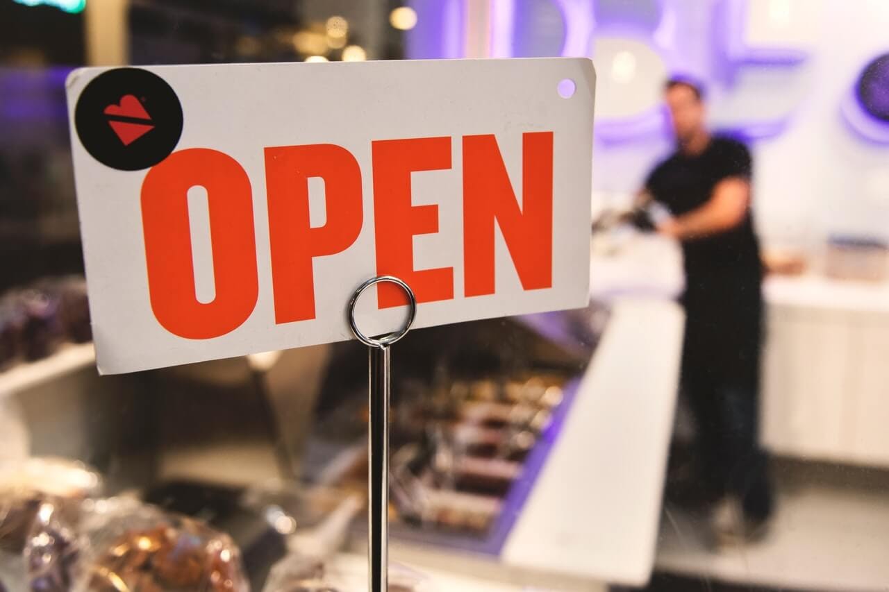 open sign in store focus man in background salesperson