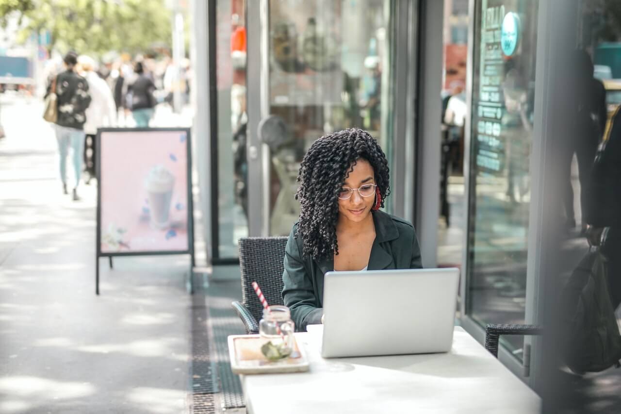 woman outside on laptop having lunch on busy street during the day