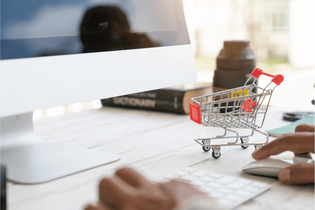 online shopping miniature cart on desk with desktop computer