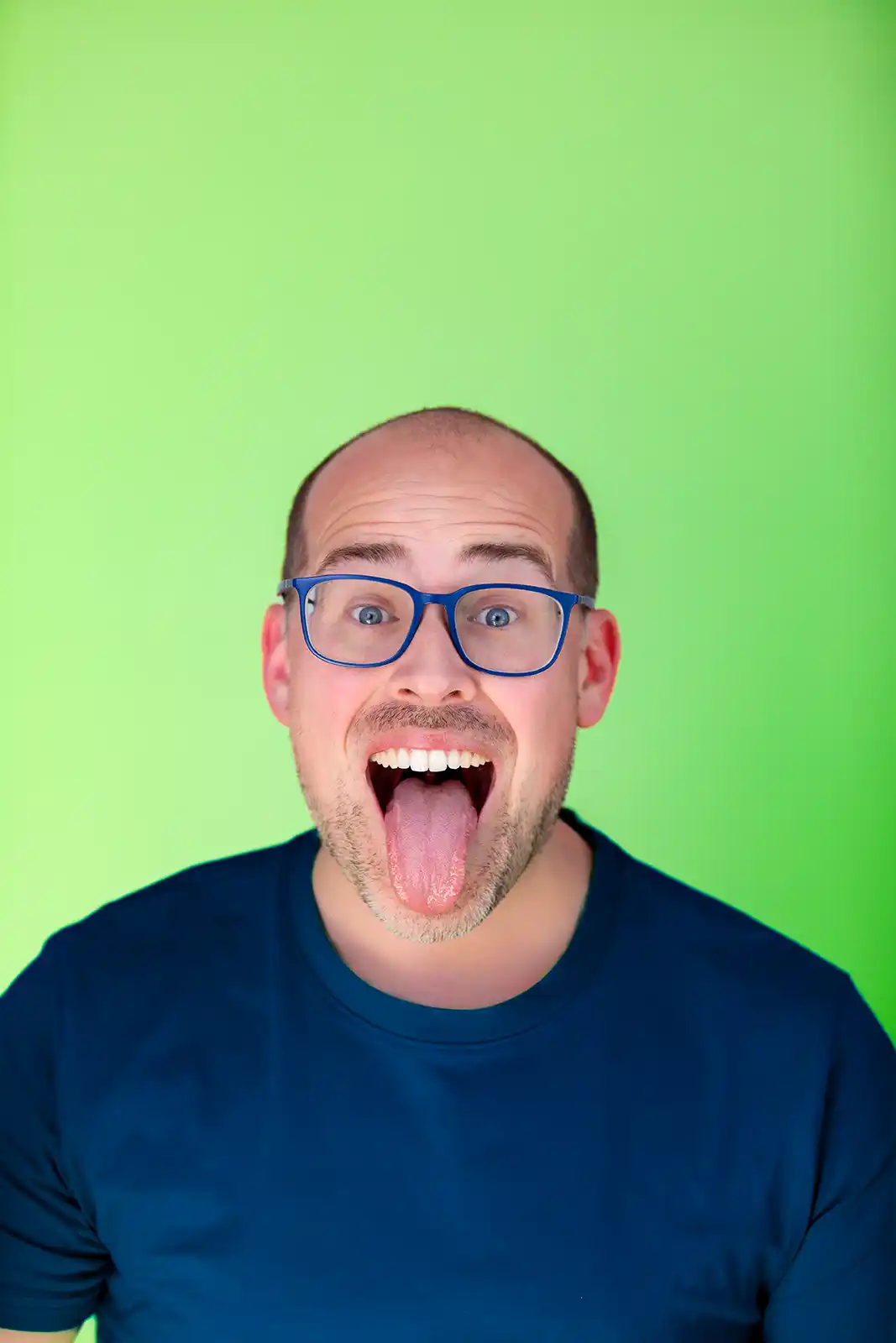 a man on a green background pokes his tongue out