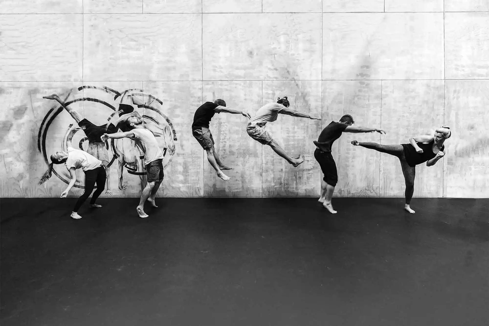 6 people jumping to different heights against a wooden backdrop