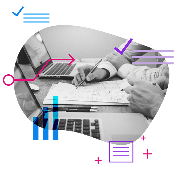 peoples hands reviewing paper work on a desk with laptops and data elements