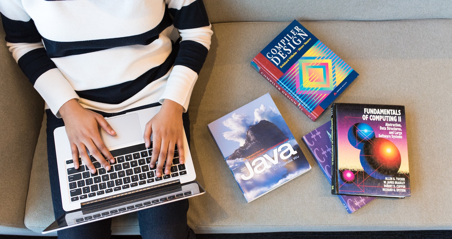 Freelancer on laptop with manuals and books next to them