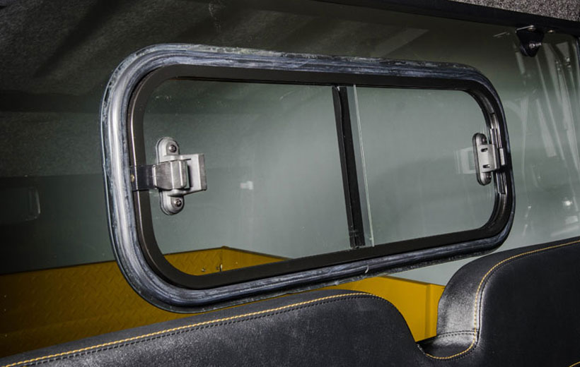 Image of a window with latches on either side in the back of a cab of a utility vehicle