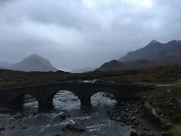 Photo of a bridge above a rushing river in the morning.