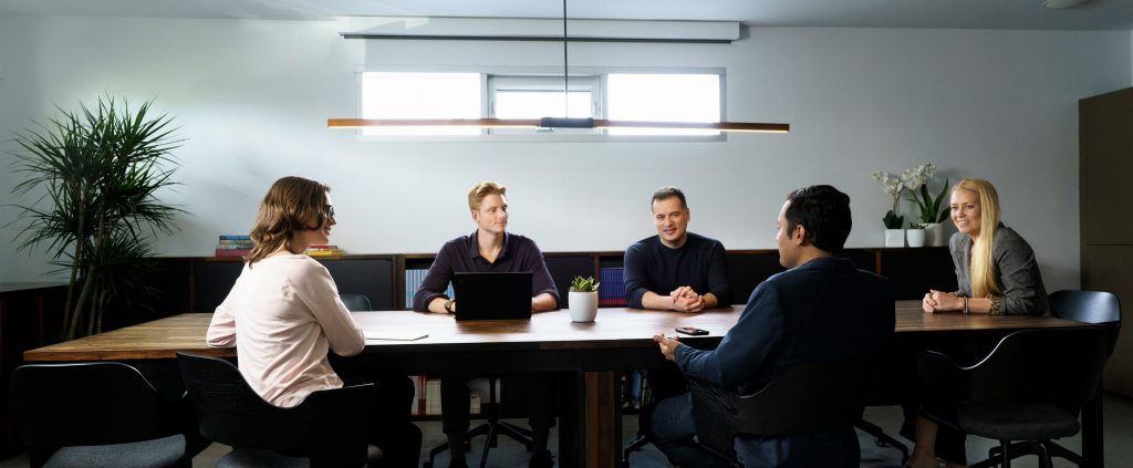 M13 employees sitting with a founder at a conference table in a meeting
