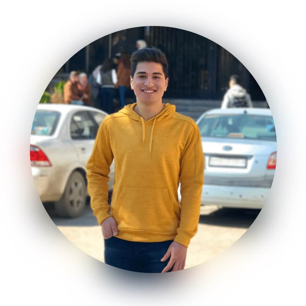  Smiling person in a yellow hoodie with a blurred street background