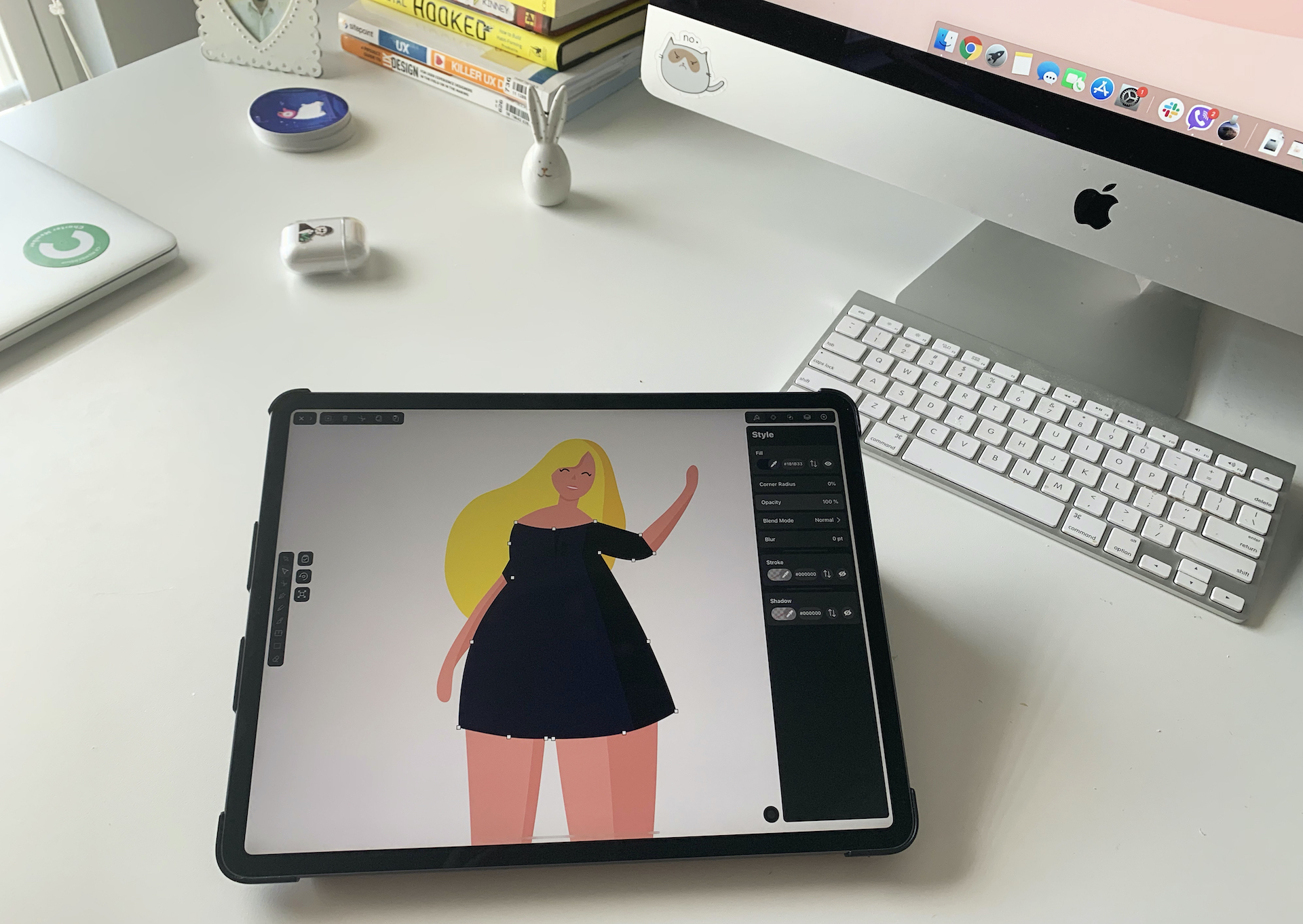 iPad displaying a female character illustration, with iMac and keyboard on a desk