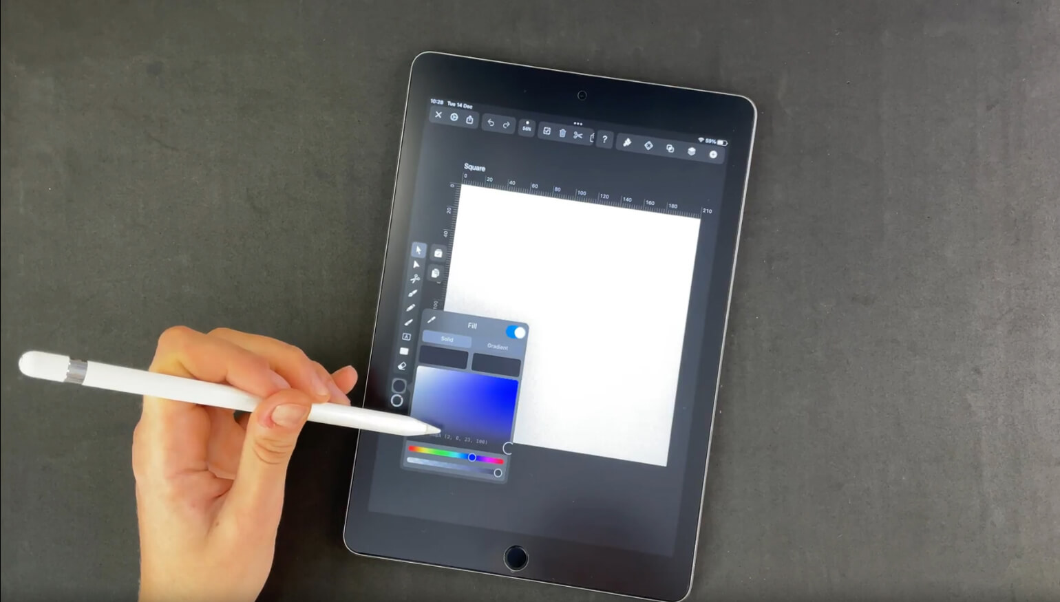 Hand holding a stylus over a digital tablet with a graphic design application open