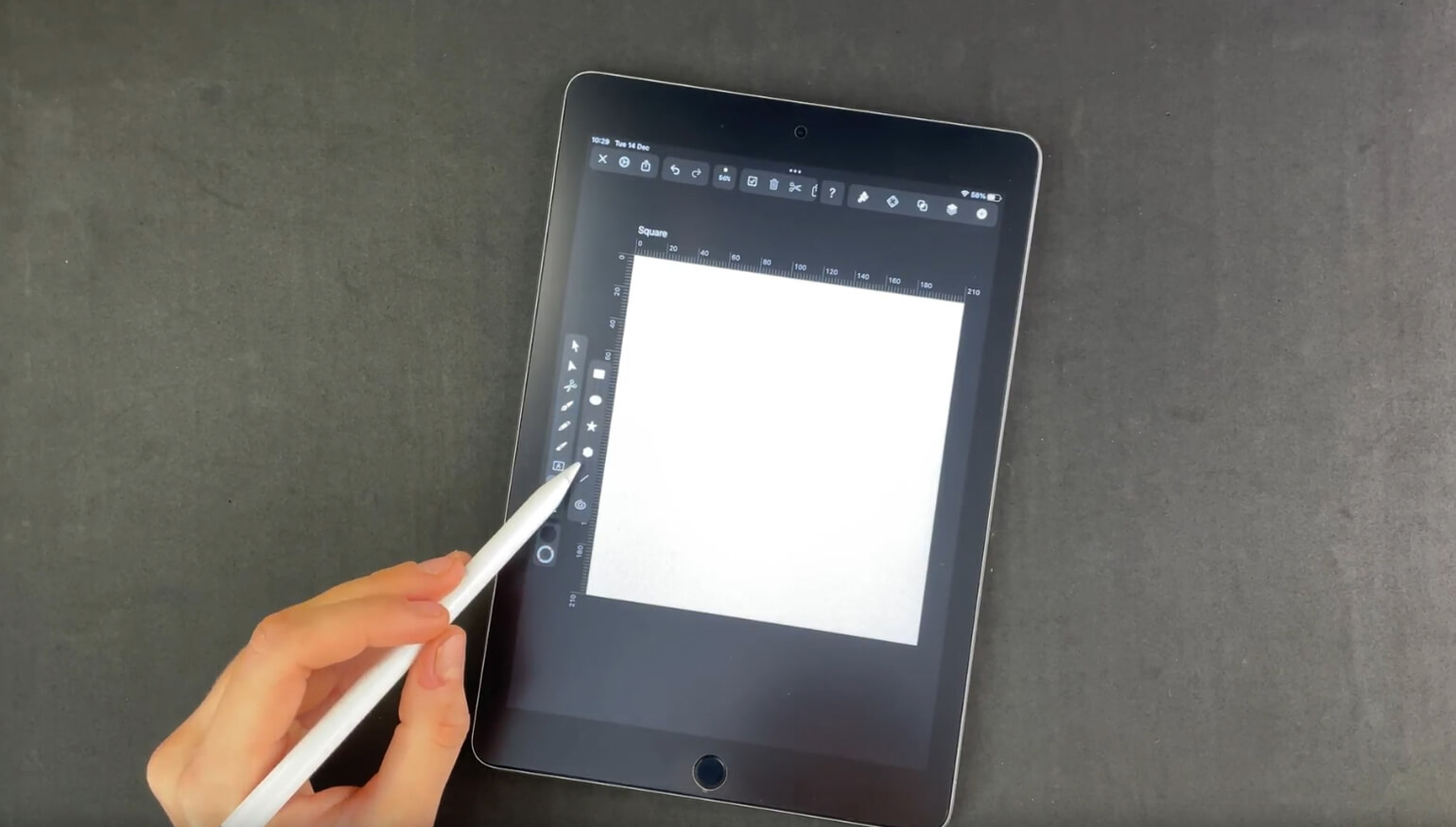 Hand with stylus pointing to a blank canvas on a graphic design app on a tablet