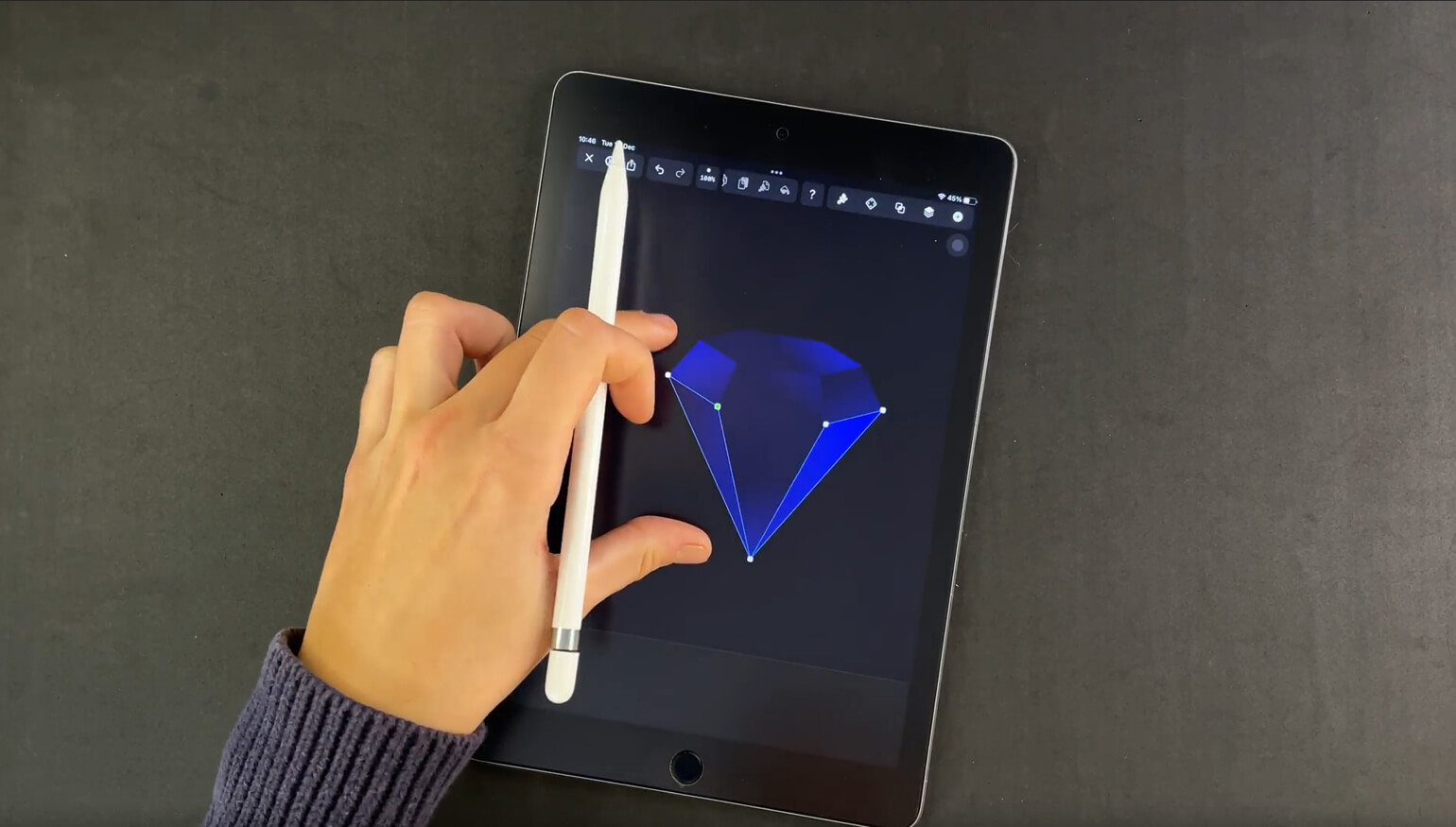 Hand holding a stylus over a tablet with a blue diamond graphic on the screen