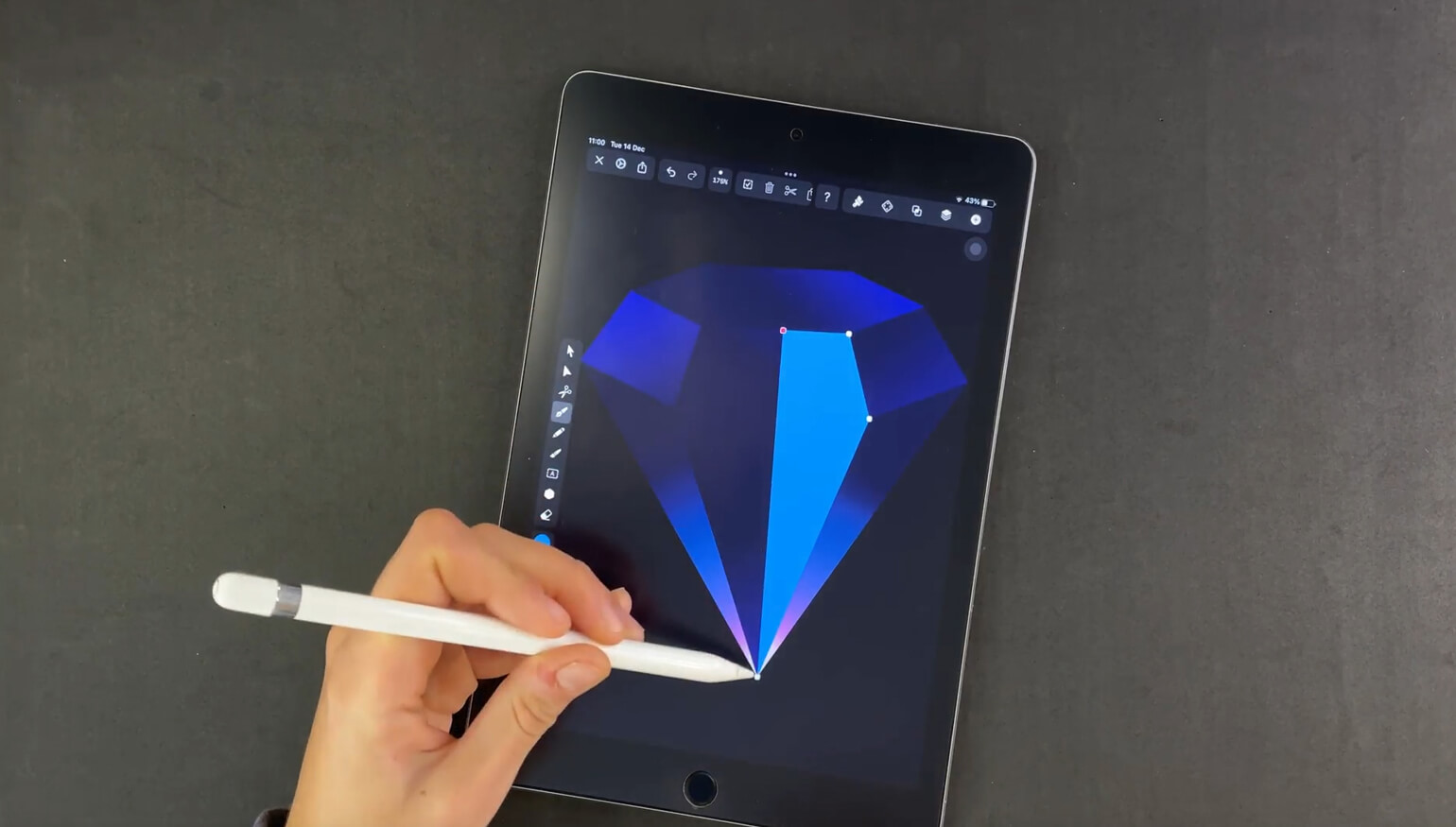 Hand holding a stylus over a tablet with a blue diamond graphic on the screen