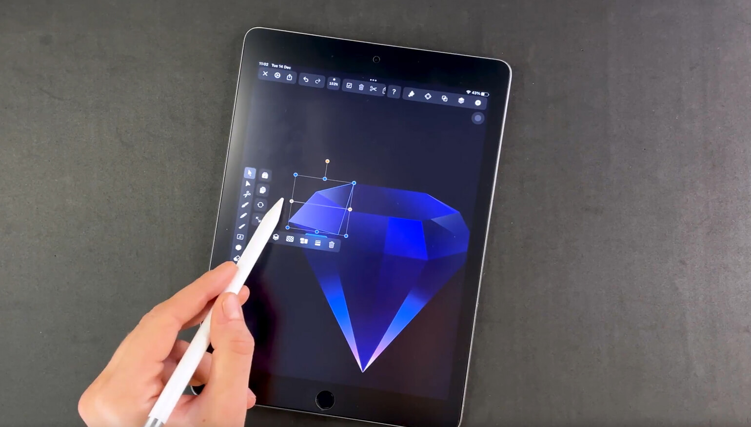 Hand with stylus editing a facet of a blue diamond graphic on a tablet