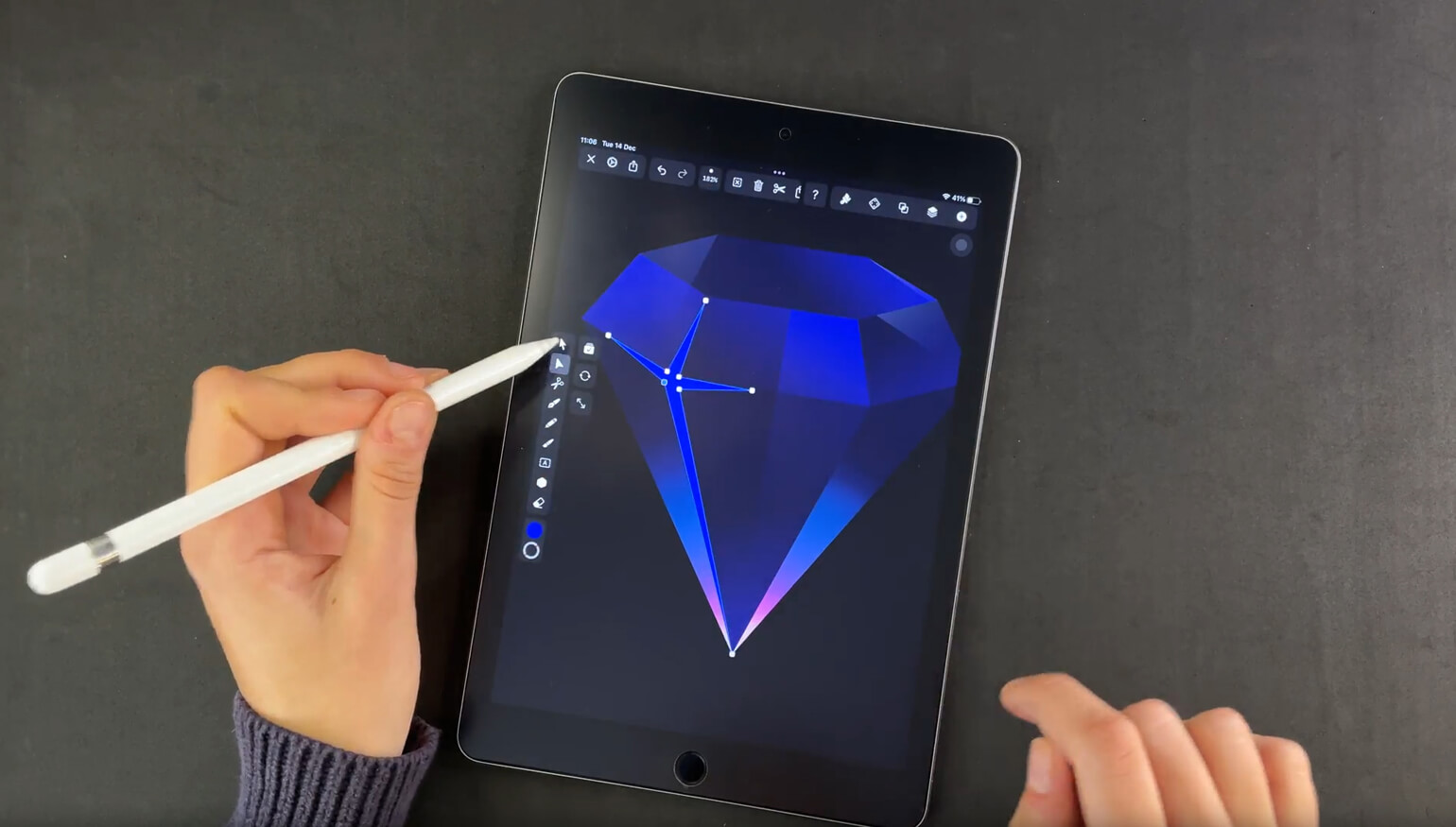 Hand with stylus and finger adjusting a blue diamond graphic on a tablet screen