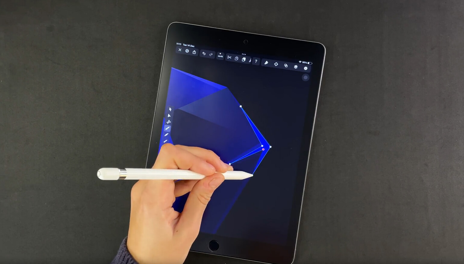 Hand holding a stylus to a tablet screen displaying geometric shape editing