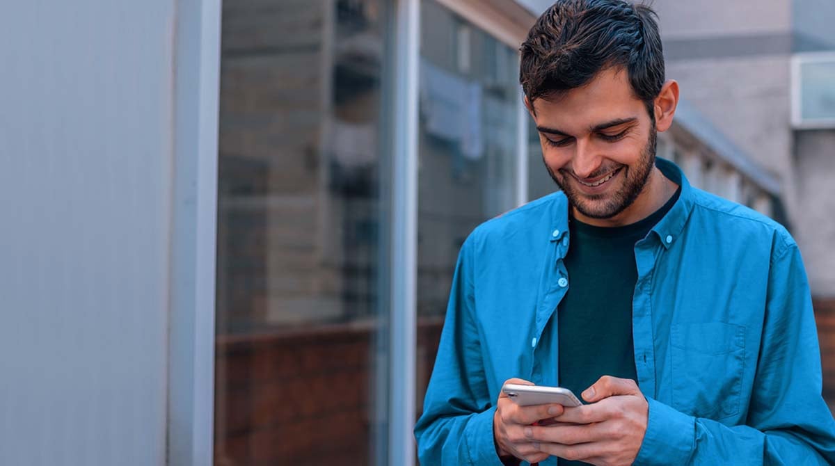 token de precatorio - homem olhando e digitando ao celular enquanto apresenta sorriso no rosto