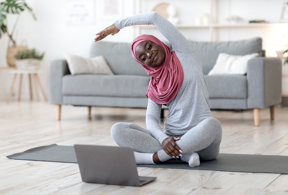 Black woman in hijab doing virtual fitness class