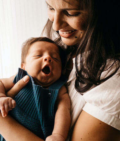 Mother holding yawning baby