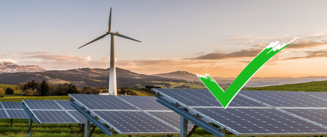 Ein Windkraftrad und Solaranlagen in der Natur mit einem grünen Haken, die unser Grünstrom Fazit symbolisieren