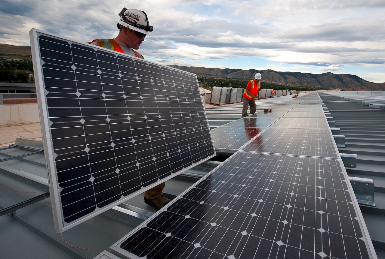 Solaranlage kaufen oder mieten - Arbeiter intallieren Solarmodule auf einem Dach