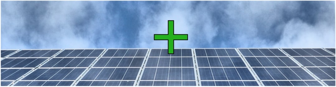 Ein grünes Plus Symbol vor einem grauen Himmel und einer Photovolataikanlage