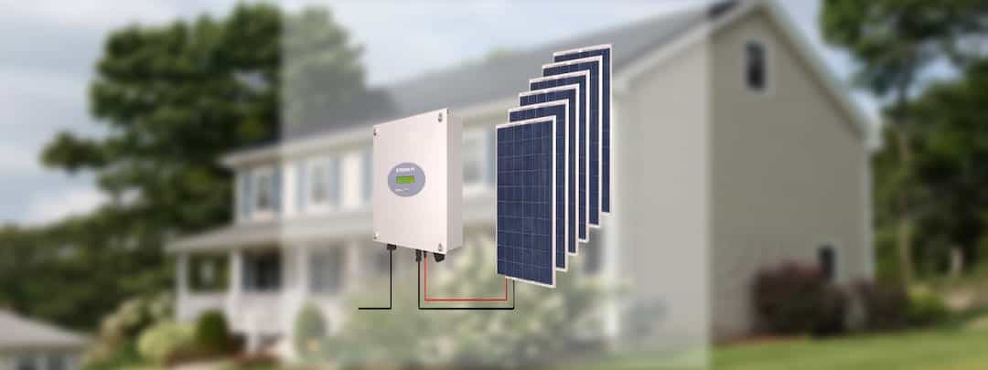 Ein Wechselrichter mit Solarpanels vor einem weißen Haus