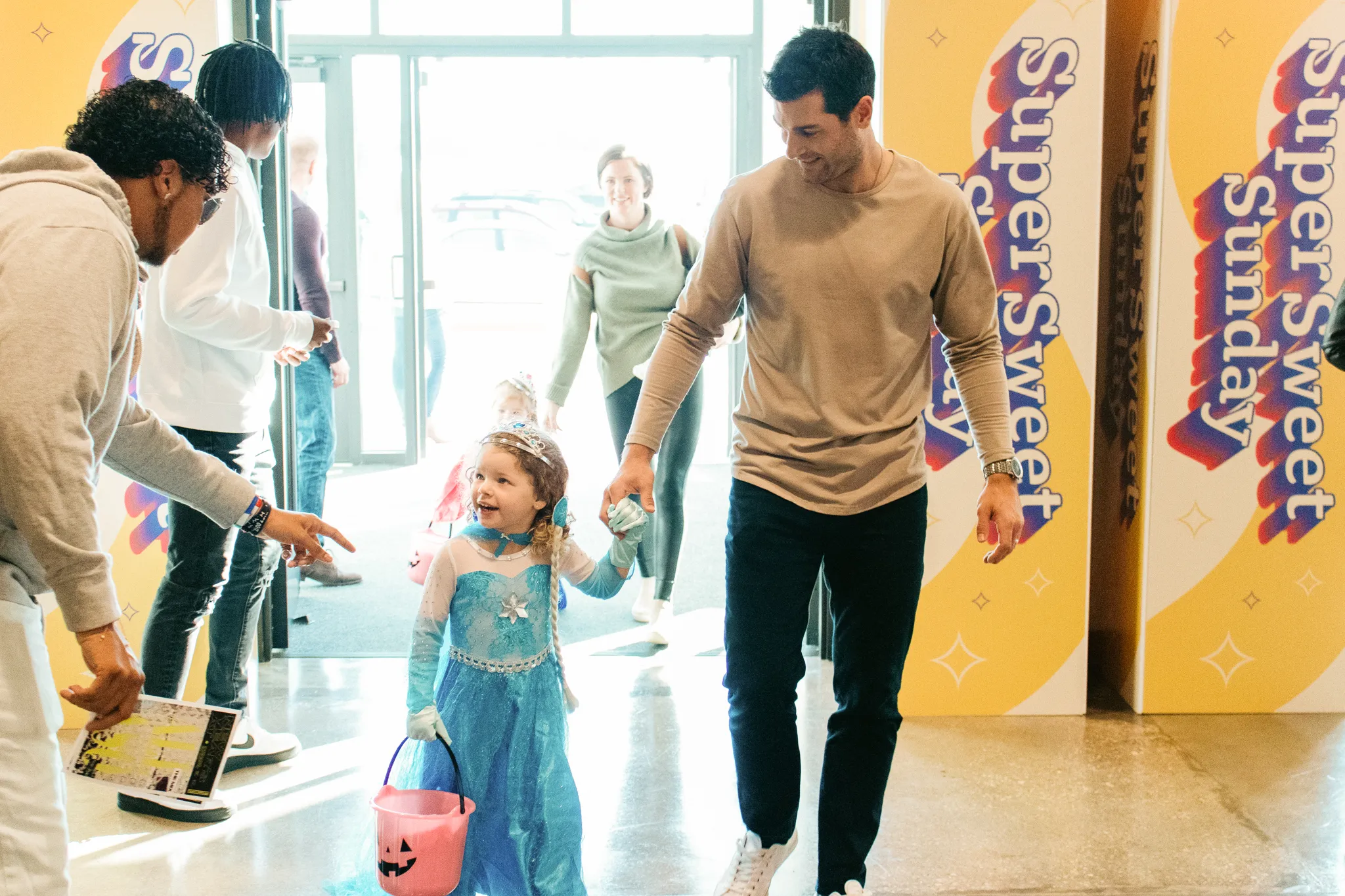 A girl dressed as a princess holding hands with her father