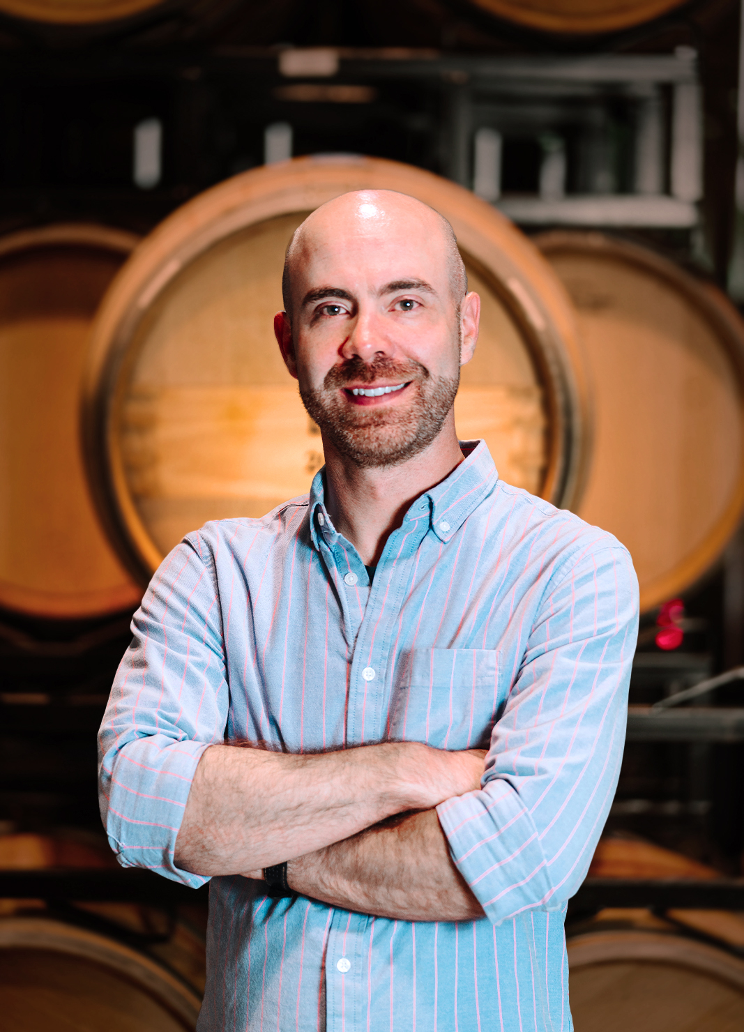 Carboy Wine Club Manager and Corporate Trainer, Kellen Brewer, standing in front of a wine barrel