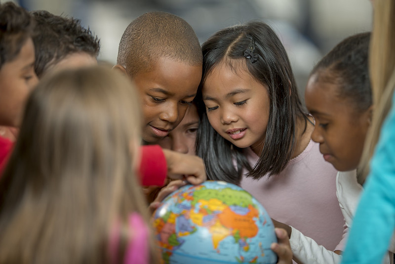 Group of children looking at a globe to learn about diversity.