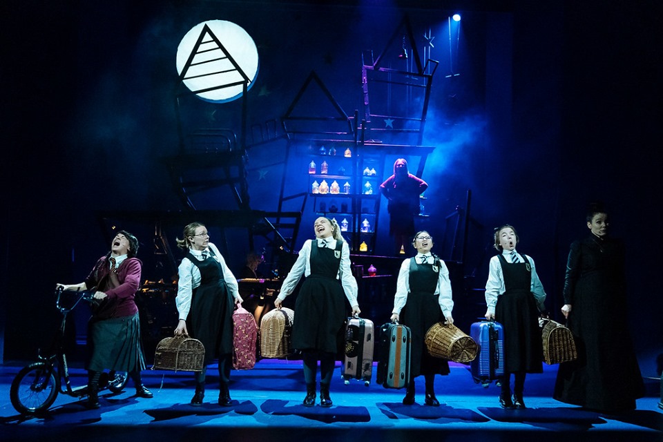 Pupils singing with their luggage on stage in the Worst Witch