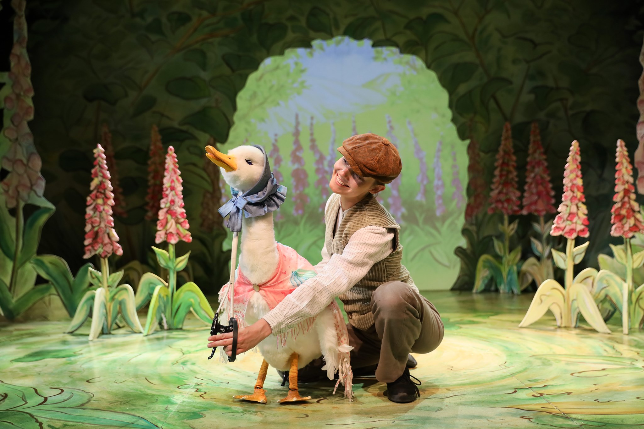 a swan puppet on stage amongst trees