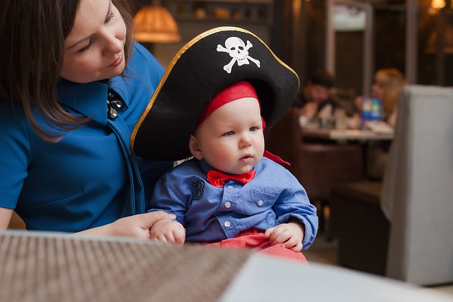 A baby tries on a pirate hat on the golden hinde