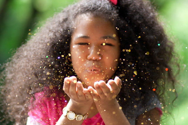 girl blowing gold glitter