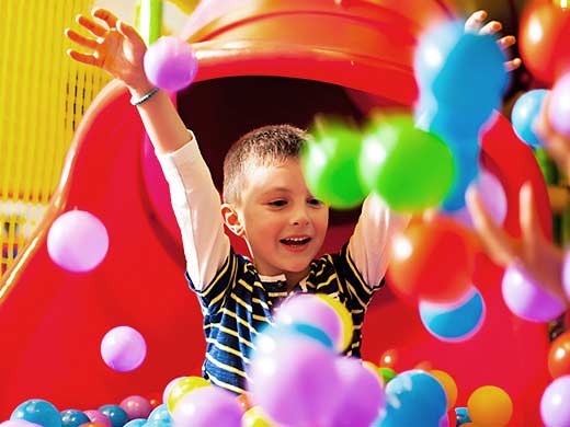 boy sliding down a slide into a ball pit at Hullabaloo Soft Play