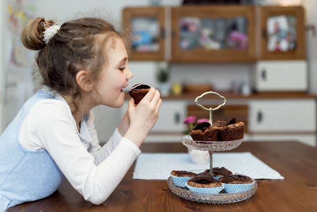 girl eating a cupcake off a stand