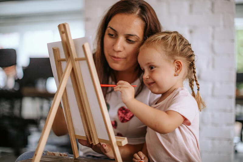 mother aiding daughter in making famous art copy for kids project