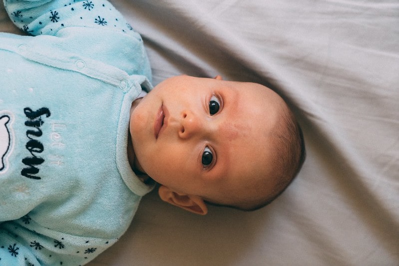 Baby in a onesie named Aaron, one of the amazing boys' names beginning with A
