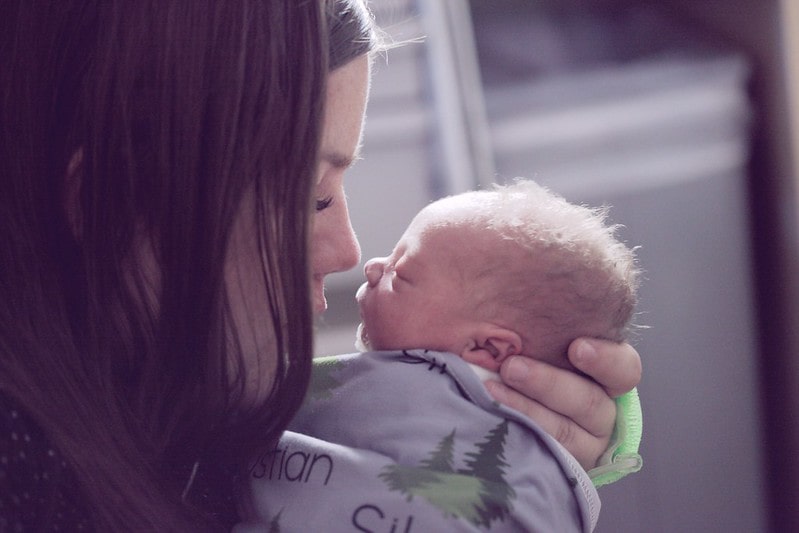 Mum kissing baby's head, who she will give a beautiful girl name to.