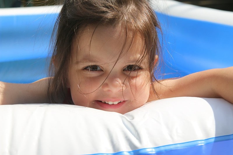 Little girl smiling while in a clean paddling pool