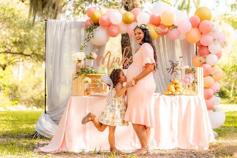 Girl kissing mum's pregnant belly