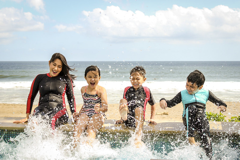 Woman and her children enjoying the outside, splashing the sea.