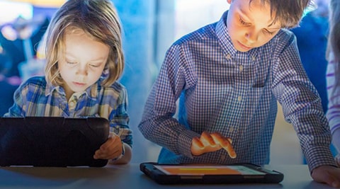 Girl and boy playing on tablets.