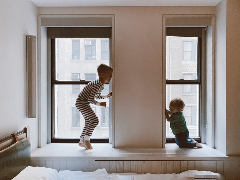 Two kids playing by the windows.
