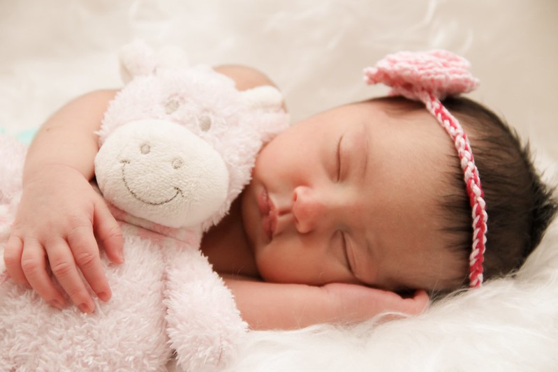 Newborn baby girl cuddling a teddy.