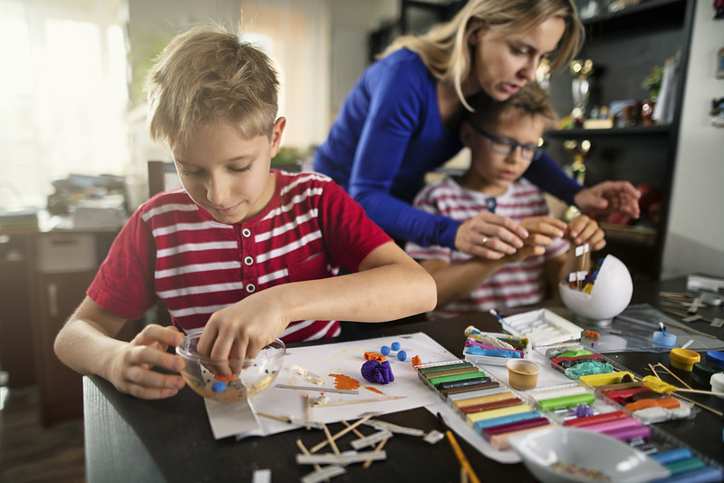 A mother and her two sons doing an experiment on the kitchen table.