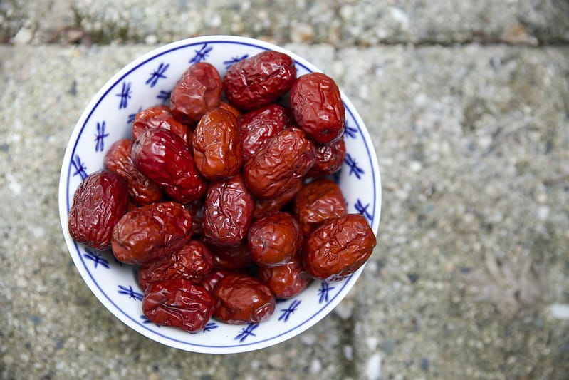 White bowl with blue designs full of large red dates.